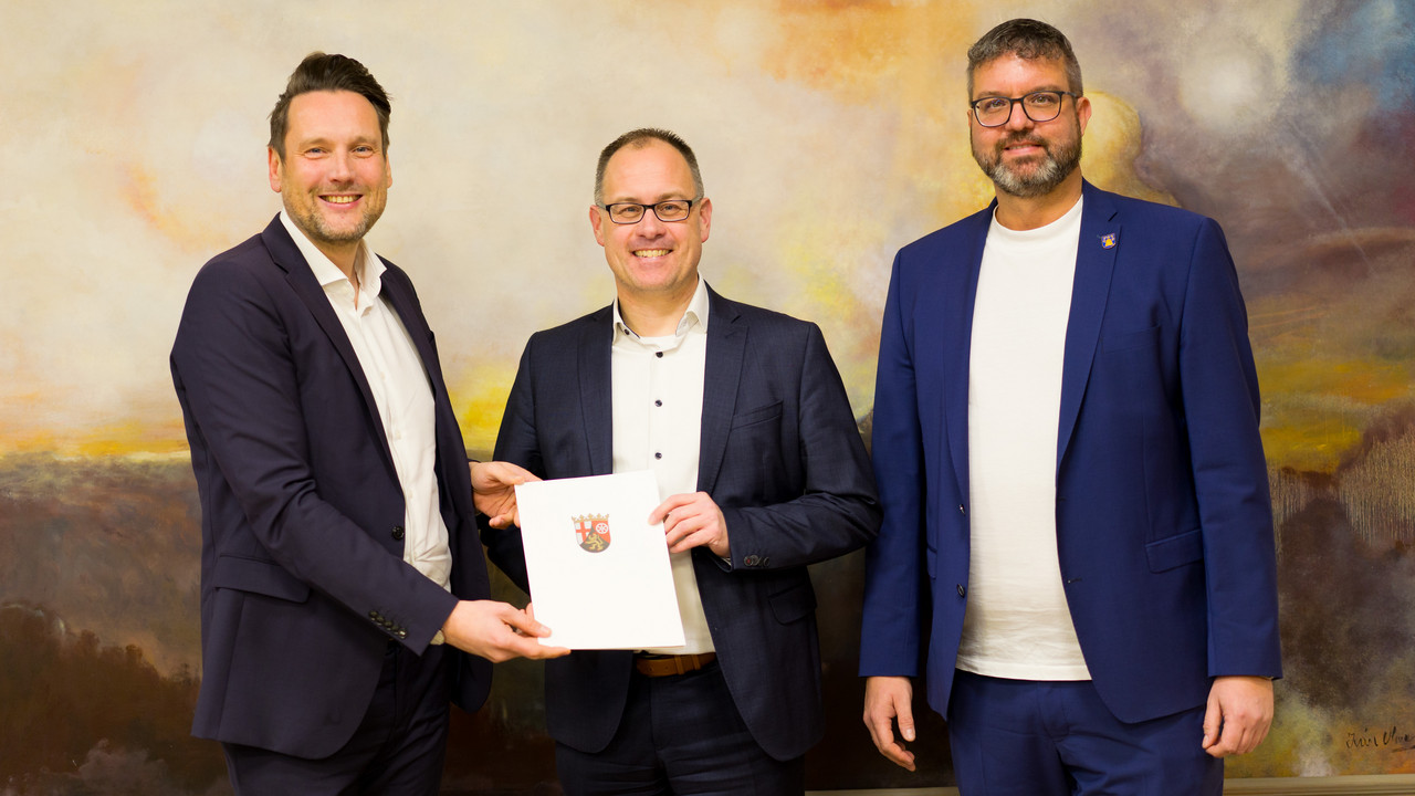 Staatssekretär Daniel Stich (l.) bei der Übergabe des Förderbescheids mit VG-Bürgermeister Jens Güllering (m.) und dem Bürgermeister der Stadt Nastätten Marco Ludwig (r.).